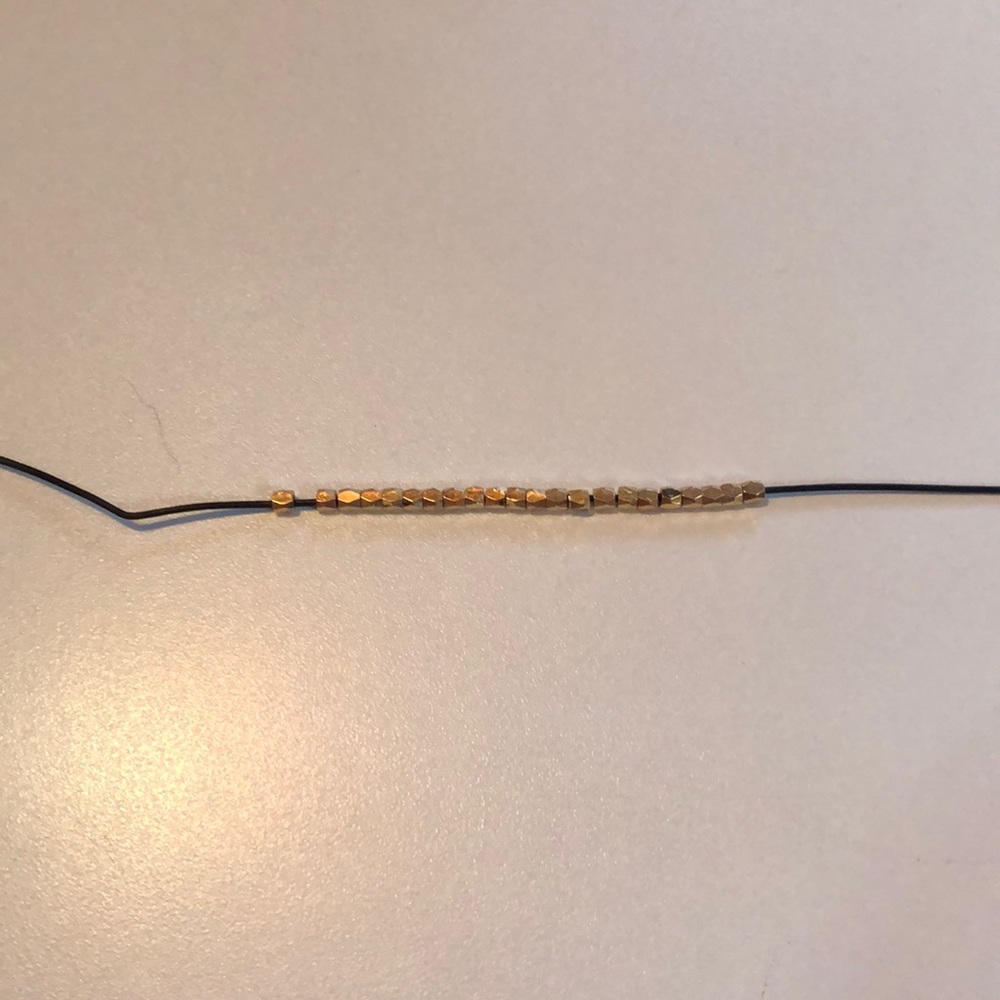 This is a black choker with gold beads